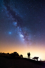 Naklejka na ściany i meble Silhouette of a couple looking at the stars and the Milky Way on a summer night in the sky of Tenerife