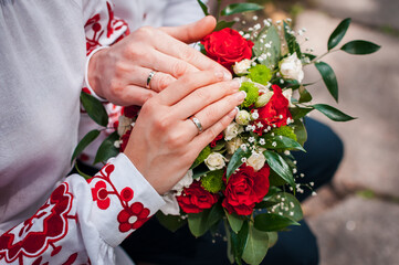 Hands of newlyweds with wedding rings on a wedding bouquet