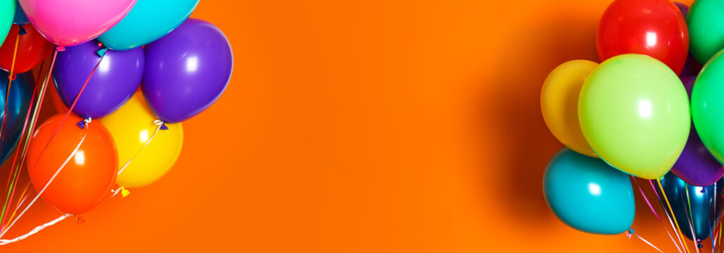 Bunches of bright balloons on orange background, space for text. Banner design