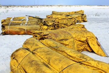 Containment boom on white sand beach ready for oil spill cleanup.
