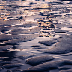 Wet beach at low tide catching the orange light of the sunset