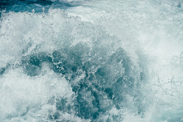 Frozen splashing in rapids of powerful mountain river. Surf of clear water  close-up. Nature background with tide of azure water. Frozen motion of splashes. Backdrop of only water. Full frame of tide.