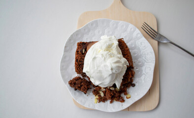 Composition on a gray background in natural sunlight. Homemade cake (chocolate sponge cake with whipped cream), top view.