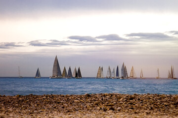 Marina regatta of sports sailing yachts on the horizon in a stormy sea with big waves and cloudy...