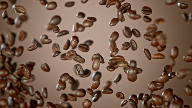 Super Slow Motion Shot of Crashing Coffee Beans on Brown Gradient Background at 1000fps.