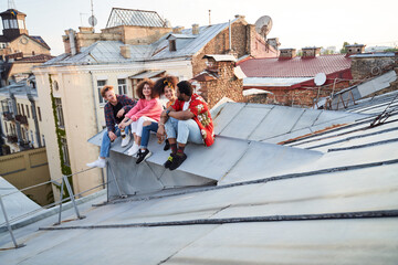 Young company on roof of old urban house