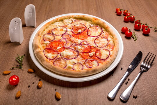 Pizza with feta and salami thin cake, cream, Italian salami, tomatoes, marinated onions, mozzarella, feta, basil