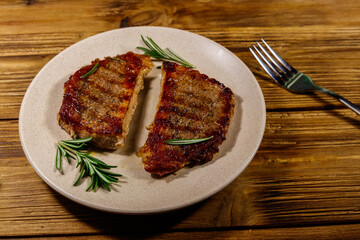 Grilled pork steaks with rosemary on wooden table