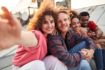 Cheerful friends taking selfie together on roof