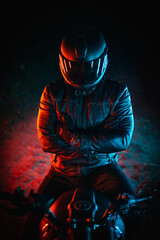 biker with black helmet and crossed arms at night and colorful lights - obrazy, fototapety, plakaty