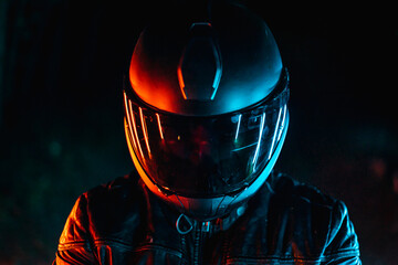 biker with black helmet at night and orange and blue lights