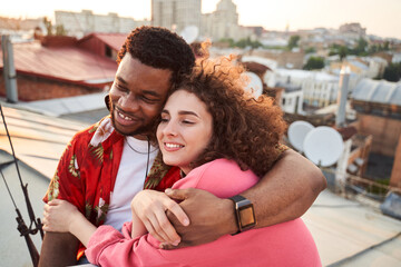 Smiling male and female in love hugging outdoors