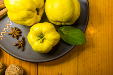 large yellow quince fruits on a ceramic plate, with anise, cinnamon, and walnuts
