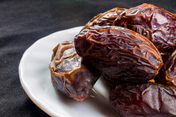 Big luxury dried date fruit in bowls on the dark surface, kurma ramadan kareem concept, close up.