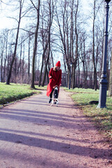 pretty young girl in redd coat playing with dog outside in green park, lifestyle people concept