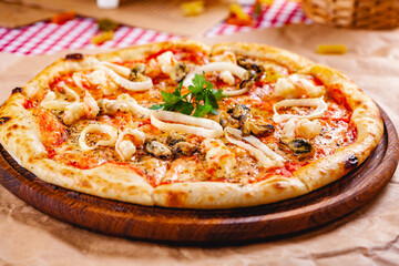 Italian Pizza with seafood and mozzarella cheese on wooden cutting board. Close up