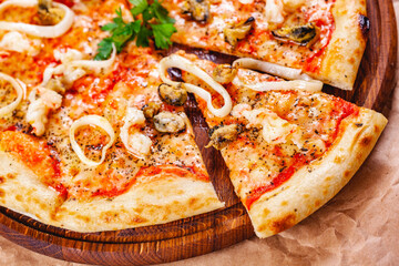Italian Pizza with seafood and mozzarella cheese on wooden cutting board. Close up