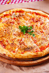 Italian Pizza with bacon, tomatoes and mozzarella cheese on wooden cutting board. Close up