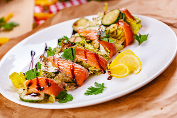 Salad with salmon, cucumber and mixed greens on white plate. Close up