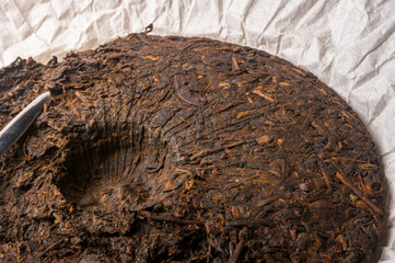 Chinese pressed PU-erh tea on wrapping paper and tea knife, close-up, macro
