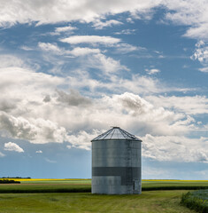 Grain silo in a farmer's field and beautiful puffy clouds in rural Alberta Canada at sunset