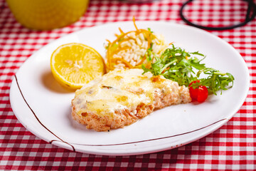 Salmon fillet served with risotto, arugula salad and lemon on white plate. Close up