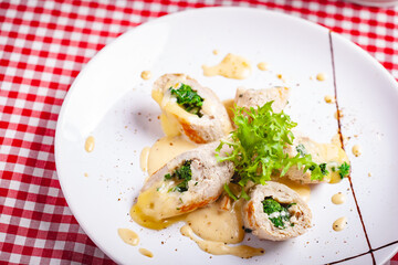 Steamed chicken cutlets stuffed with spinach on white plate. Close up