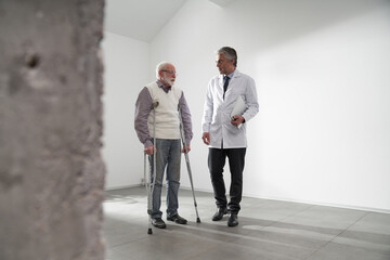Fototapeta premium Experienced doctor communicating with patient on crutches