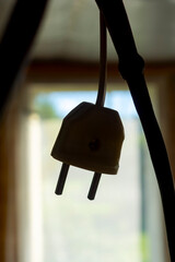 Power plug on electrical wire dangles by the doorway indoors