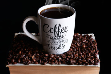 cup of coffee with smoke on a book and coffee beans