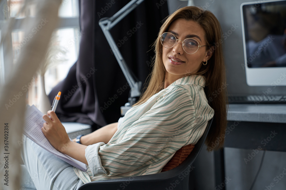 Wall mural Smiling beautiful woman with papers and pen indoors