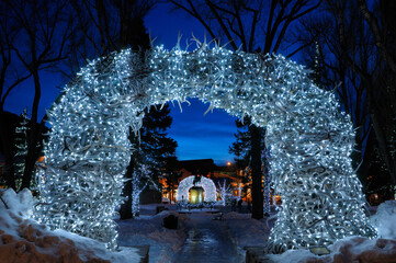 Brightly lit Elk antler arches in Jackson Wyoming town square in winter at twilight