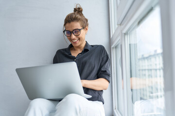 Happy businesswoman using laptop on window still