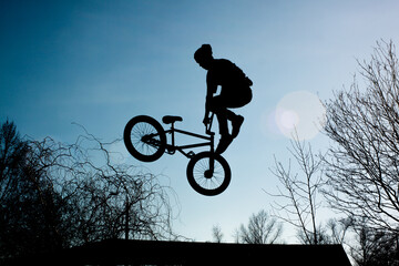 View from below strong athlete jumping in air. Guy performs tricks on a bike. Concept of adrenaline.