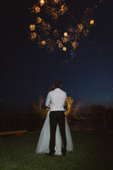 The bride and groom look at the wedding night fireworks.