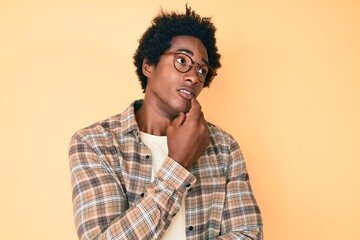 Handsome african american man with afro hair wearing casual clothes and glasses thinking...