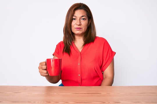 Middle Age Brunette Woman Drinking A Cup Of Coffee Sitting On The Table Thinking Attitude And Sober Expression Looking Self Confident