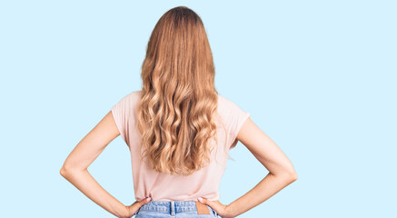 Young beautiful caucasian woman with blond hair wearing casual clothes standing backwards looking...