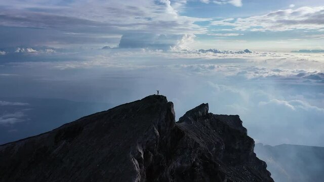 climbing a volcano. Higher than clouds. 4k video. A man walks along the high mountains. Vulcano agung. a man stands on the edge of a crater. Eruption. Batur and abang in Kintmani. hands up