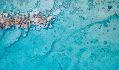 An aerial view of the beautiful Mediterranean sea, where you can see a horizontal textured line of rocks underwater  and the clean turquoise water, Horizontal Shot for banner or backround