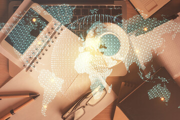 Double exposure of business theme hologram over desktop with phone. Top view. Mobile international...