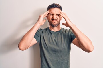 Young handsome man wearing casual t-shirt standing over isolated white background with hand on head, headache because stress. Suffering migraine.
