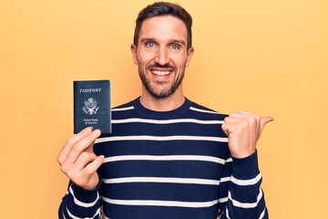 Young handsome tourist man holding united states passport over isolated yellow background pointing...