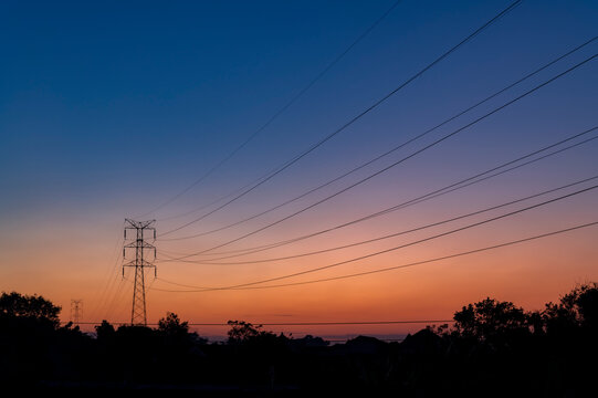 High voltage power line silhouette view with sunrise sky background