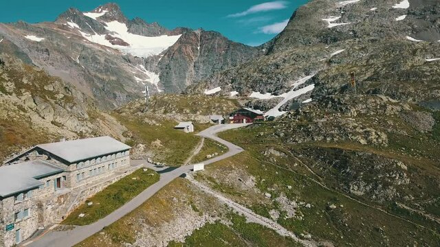 Widok na mały hotel w g&oacute;rskich szwajcarskich alpach na   kt&oacute;rym widać flagę Szwajcarii i wąskie g&oacute;rskie drogi i ścieżki