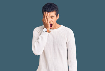Fototapeta premium Young african amercian man wearing casual clothes yawning tired covering half face, eye and mouth with hand. face hurts in pain.