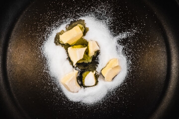 Preparing an applesauce, on a frying pan melt butter and sugar to make caramel.