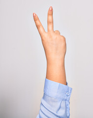 Hand of caucasian young woman doing victory symbol showing number two with streched fingers raised up over isolated white background
