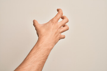 Hand of caucasian young man showing fingers over isolated white background grasping aggressive and scary with fingers, violence and frustration