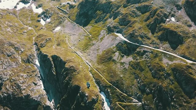 Widok na alpejskie szczyty g&oacute;r przecięte wąskimi drogami w ciepły słoneczny dzień